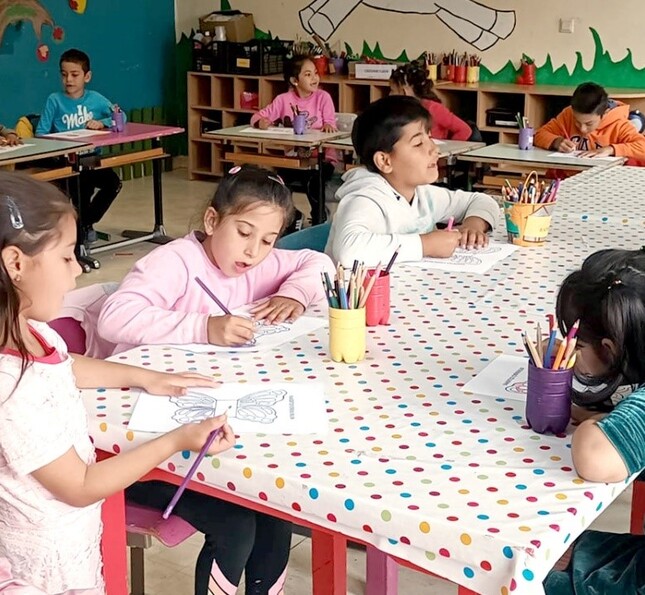 Kinder sitzen gemeinsam an einem Tisch und arbeiten an Hausaufgabeninsam in der Schule